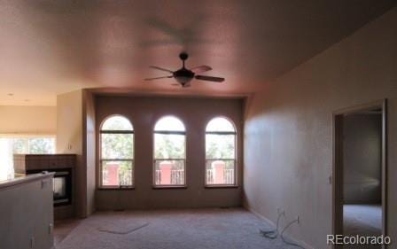 unfurnished living room featuring light carpet and ceiling fan