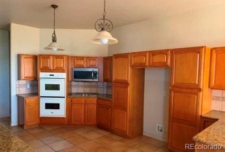 kitchen with pendant lighting, appliances with stainless steel finishes, light tile patterned floors, and decorative backsplash