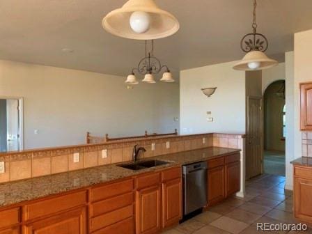 kitchen featuring tile patterned floors, sink, decorative light fixtures, and stainless steel dishwasher