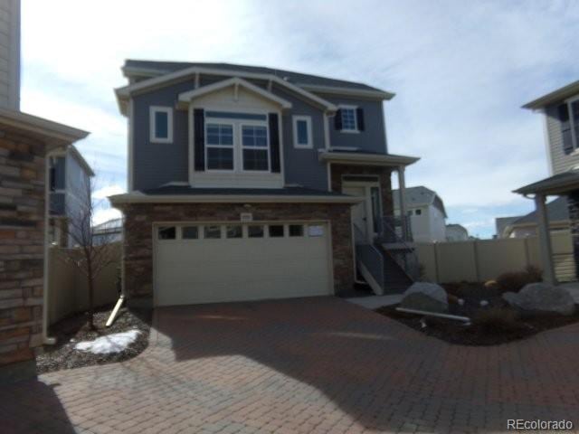 view of front of property with decorative driveway, fence, and an attached garage