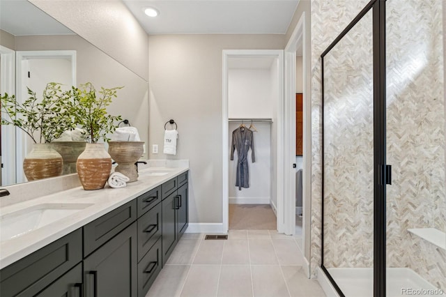bathroom with a sink, a shower stall, tile patterned flooring, double vanity, and a spacious closet