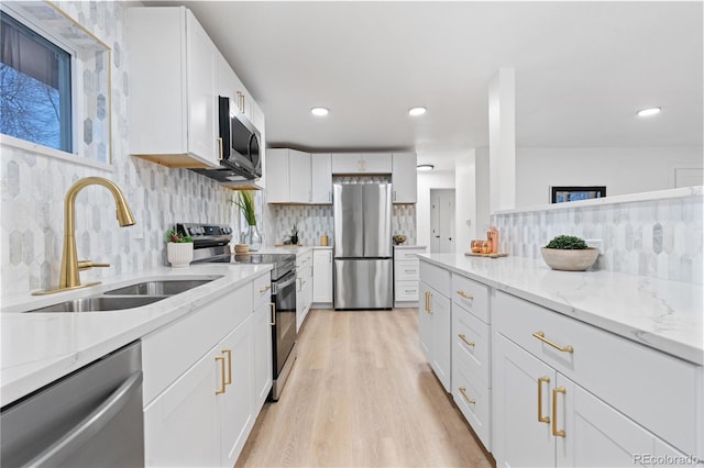 kitchen featuring white cabinetry, decorative backsplash, appliances with stainless steel finishes, and light stone counters