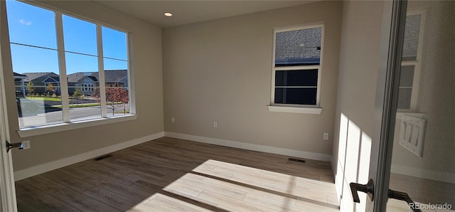 empty room with a wealth of natural light and hardwood / wood-style flooring