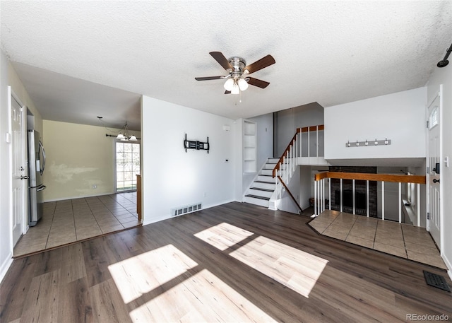 unfurnished living room with ceiling fan, a textured ceiling, and hardwood / wood-style flooring