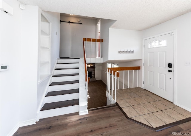 entrance foyer with a fireplace, a textured ceiling, and dark hardwood / wood-style floors