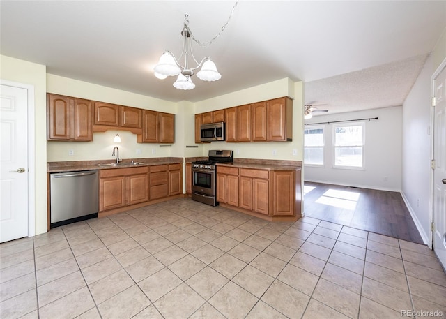 kitchen with ceiling fan with notable chandelier, sink, light tile patterned floors, appliances with stainless steel finishes, and decorative light fixtures