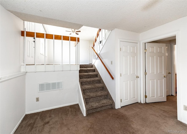 stairway with carpet, a textured ceiling, and ceiling fan