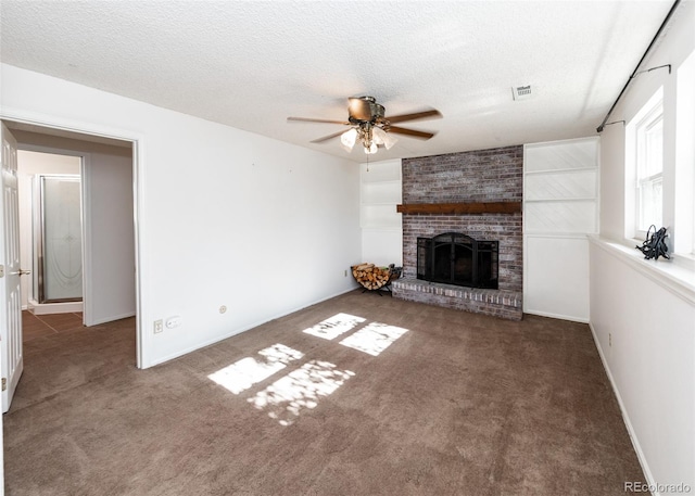 unfurnished living room featuring dark colored carpet, ceiling fan, a textured ceiling, and a brick fireplace