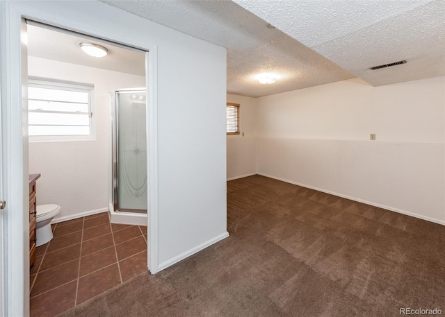 basement featuring dark carpet and a textured ceiling