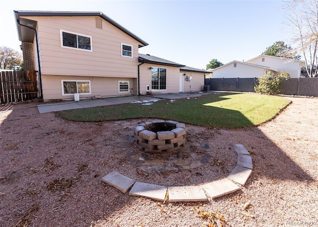 back of property with a lawn, a patio area, and a fire pit