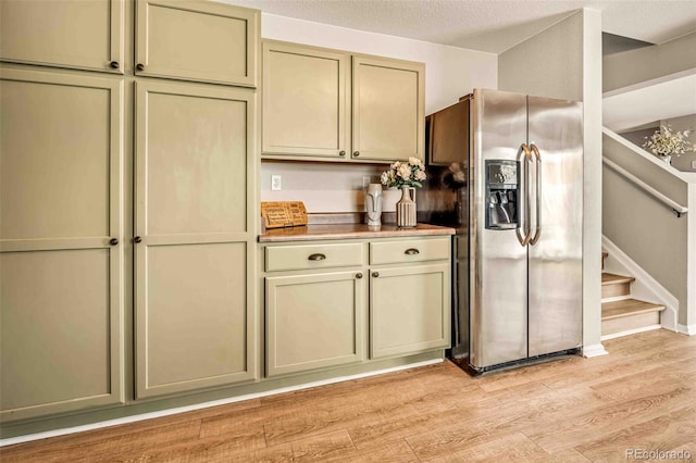 kitchen featuring cream cabinets, light hardwood / wood-style floors, stainless steel fridge with ice dispenser, and a textured ceiling