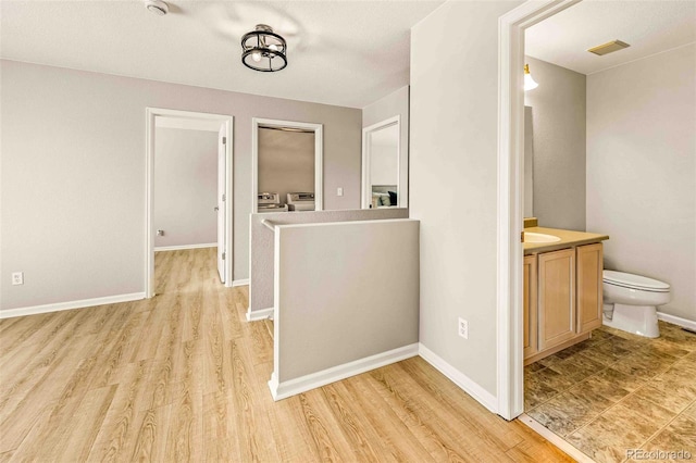 hallway featuring washer and dryer, sink, and light hardwood / wood-style flooring