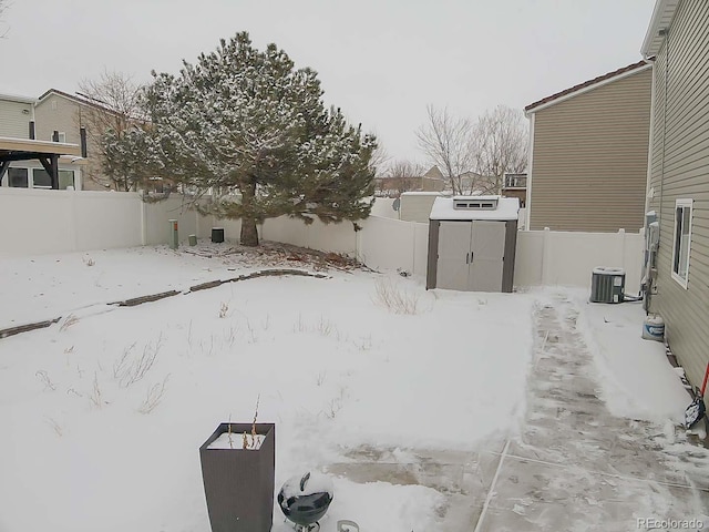 yard layered in snow with a storage shed and central air condition unit