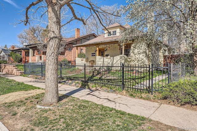 bungalow-style house featuring a chimney and a fenced front yard