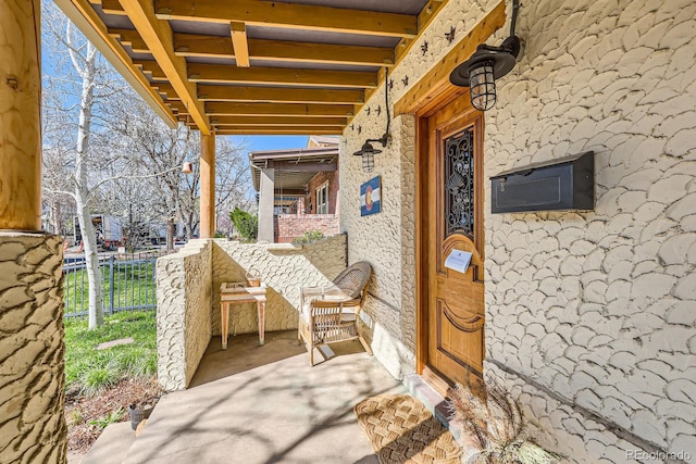 entrance to property featuring fence and covered porch