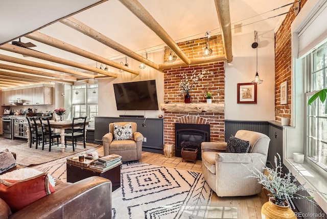living room featuring wainscoting, wood finished floors, beam ceiling, and a fireplace