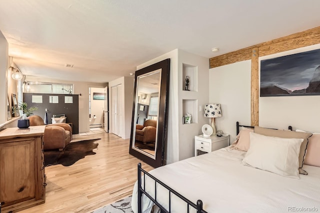 bedroom with baseboard heating, light wood-style floors, and visible vents