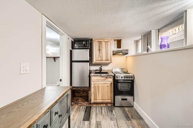 kitchen with a sink, a textured ceiling, exhaust hood, appliances with stainless steel finishes, and dark wood-type flooring