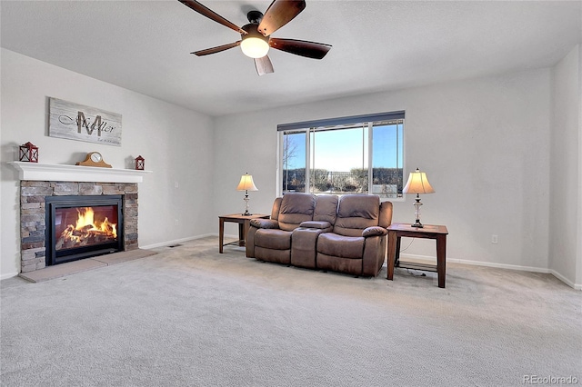 living room featuring ceiling fan, light carpet, a textured ceiling, and a fireplace