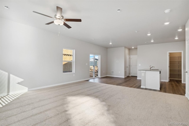 unfurnished living room with ceiling fan, sink, and dark hardwood / wood-style floors