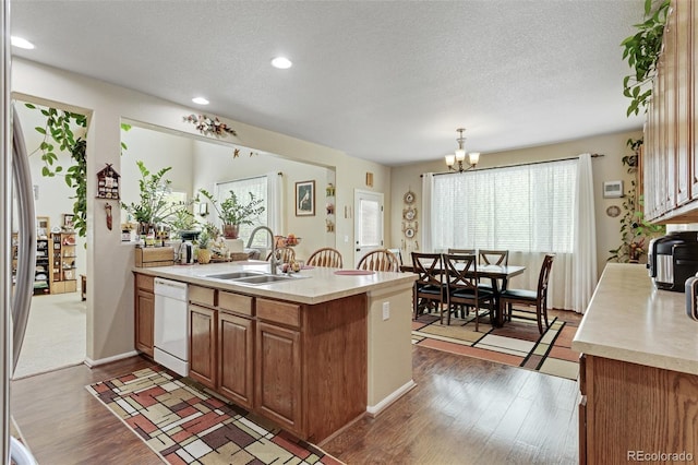 13415 Kearney St, Thornton, CO 80602 - kitchen featuring dishwasher, a sink, light countertops, brown cabinets, and wood finished floors