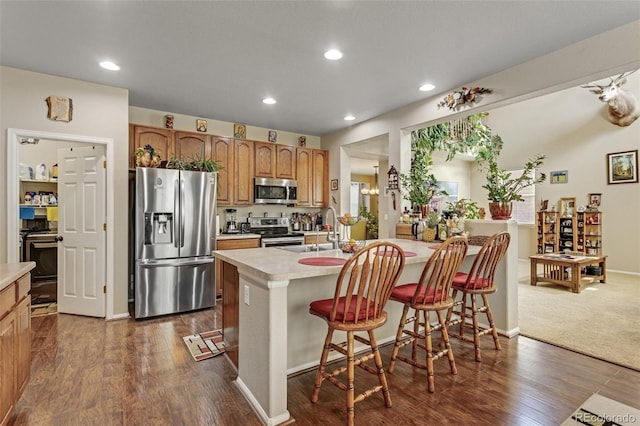 13415 Kearney St, Thornton, CO 80602 - kitchen with stainless steel appliances, a sink, light countertops, a kitchen bar, and recessed lighting