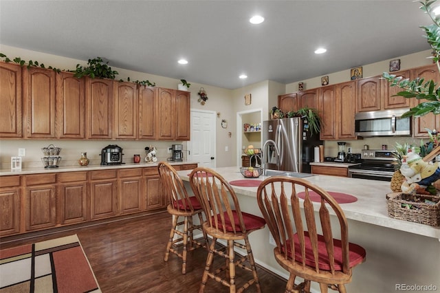 13415 Kearney St, Thornton, CO 80602 - kitchen featuring appliances with stainless steel finishes, a breakfast bar, brown cabinetry, light countertops, and recessed lighting