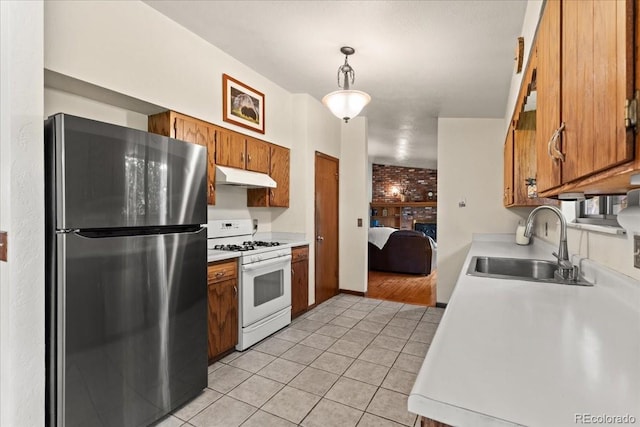 8427 S Custer Ln, Evergreen, CO 80439 - kitchen featuring freestanding refrigerator, white gas stove, under cabinet range hood, light tile patterned floors, and light countertops