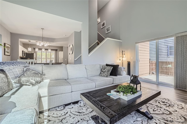 living room featuring wood-type flooring, a high ceiling, and a chandelier