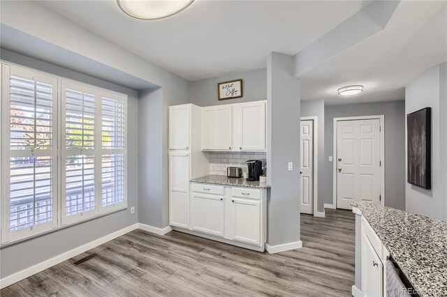 kitchen with white cabinets, light stone counters, and light hardwood / wood-style floors