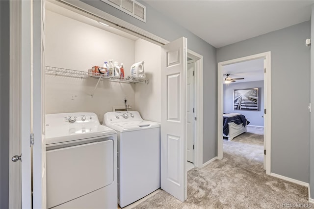 laundry area with independent washer and dryer, light colored carpet, and ceiling fan