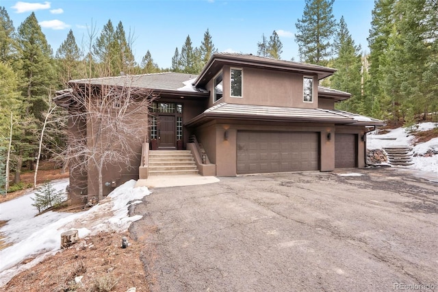 view of front of house with aphalt driveway, stucco siding, a tiled roof, and a garage