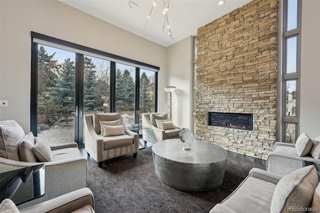 living room featuring a stone fireplace and an inviting chandelier