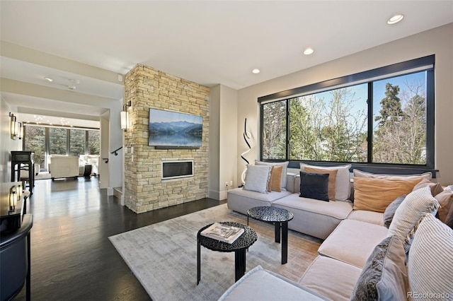 living area featuring baseboards, a stone fireplace, recessed lighting, and dark wood-style flooring
