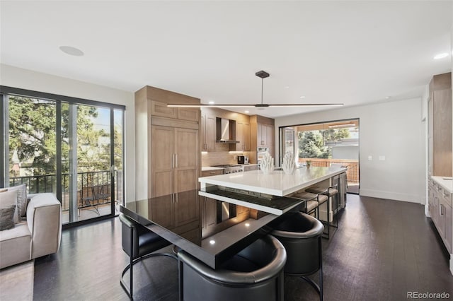 kitchen with dark wood finished floors, wall chimney range hood, baseboards, and light countertops