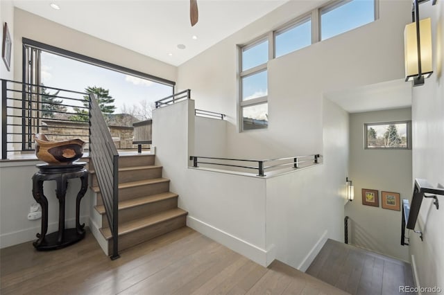 stairway featuring hardwood / wood-style flooring, baseboards, and recessed lighting