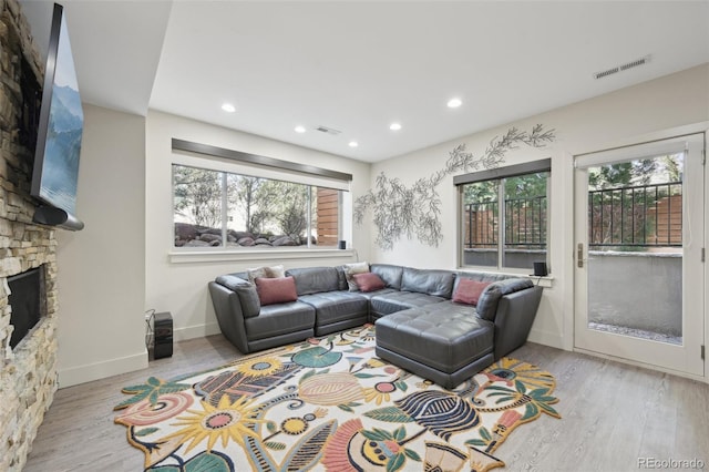 living room with a stone fireplace, visible vents, and plenty of natural light