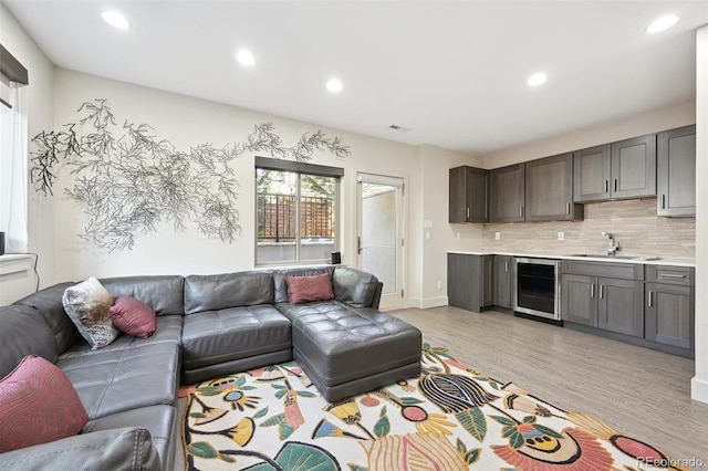 living room with light wood-style flooring, visible vents, beverage cooler, and recessed lighting