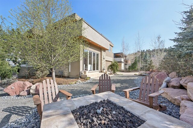 view of home's exterior featuring stucco siding, entry steps, and an outdoor fire pit