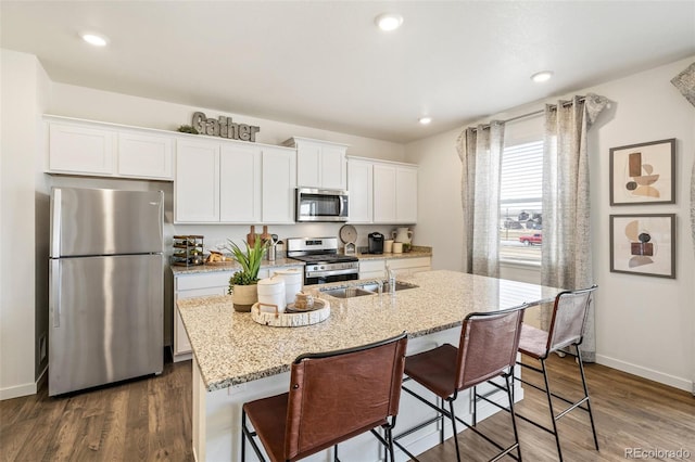 kitchen with a kitchen bar, a kitchen island with sink, white cabinetry, and appliances with stainless steel finishes