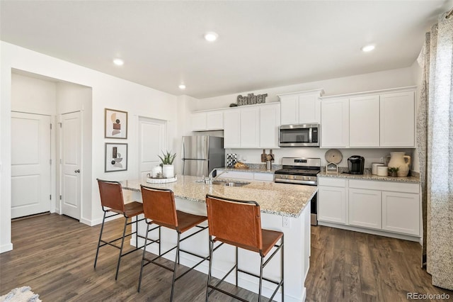 kitchen with sink, white cabinets, stainless steel appliances, and an island with sink