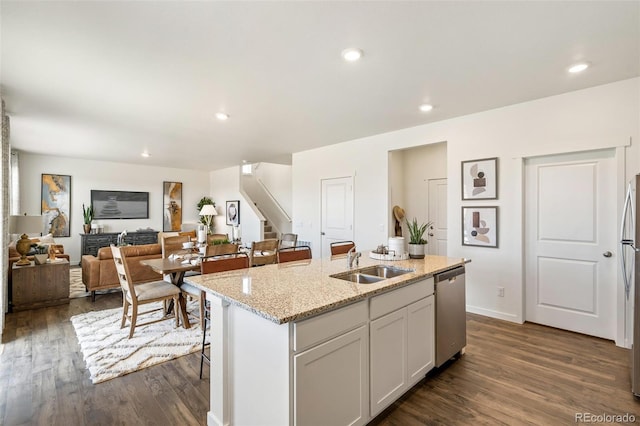 kitchen featuring light stone counters, white cabinetry, stainless steel appliances, and an island with sink