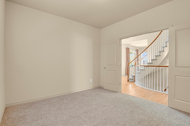 unfurnished room with carpet, stairway, and baseboards