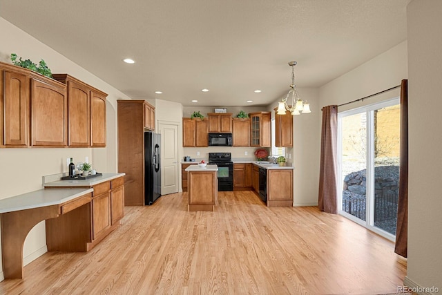 kitchen with brown cabinetry, light wood-style floors, glass insert cabinets, light countertops, and black appliances