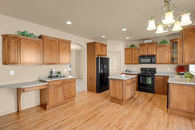 kitchen featuring arched walkways, light countertops, a center island, black appliances, and light wood finished floors