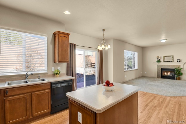 kitchen with a sink, black dishwasher, light countertops, open floor plan, and brown cabinets