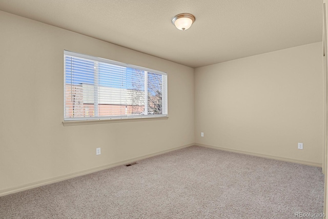 carpeted spare room featuring baseboards, visible vents, and a textured ceiling