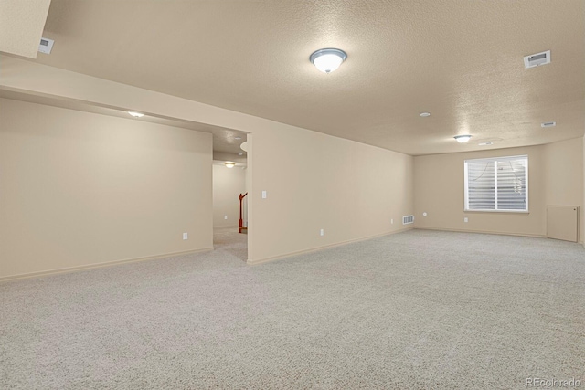 empty room with light carpet, stairway, a textured ceiling, and visible vents