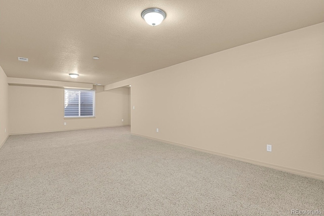 unfurnished room with a textured ceiling, light carpet, visible vents, and baseboards