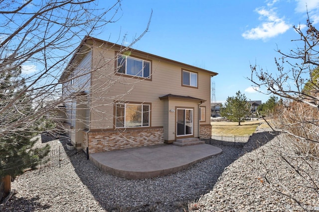 rear view of property with entry steps, brick siding, and a patio